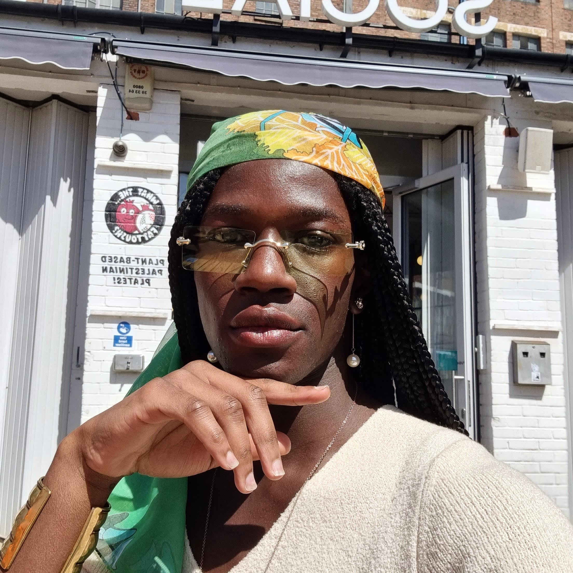Selfie of a Black woman with braids, wearing sunglasses, staring into the camera.